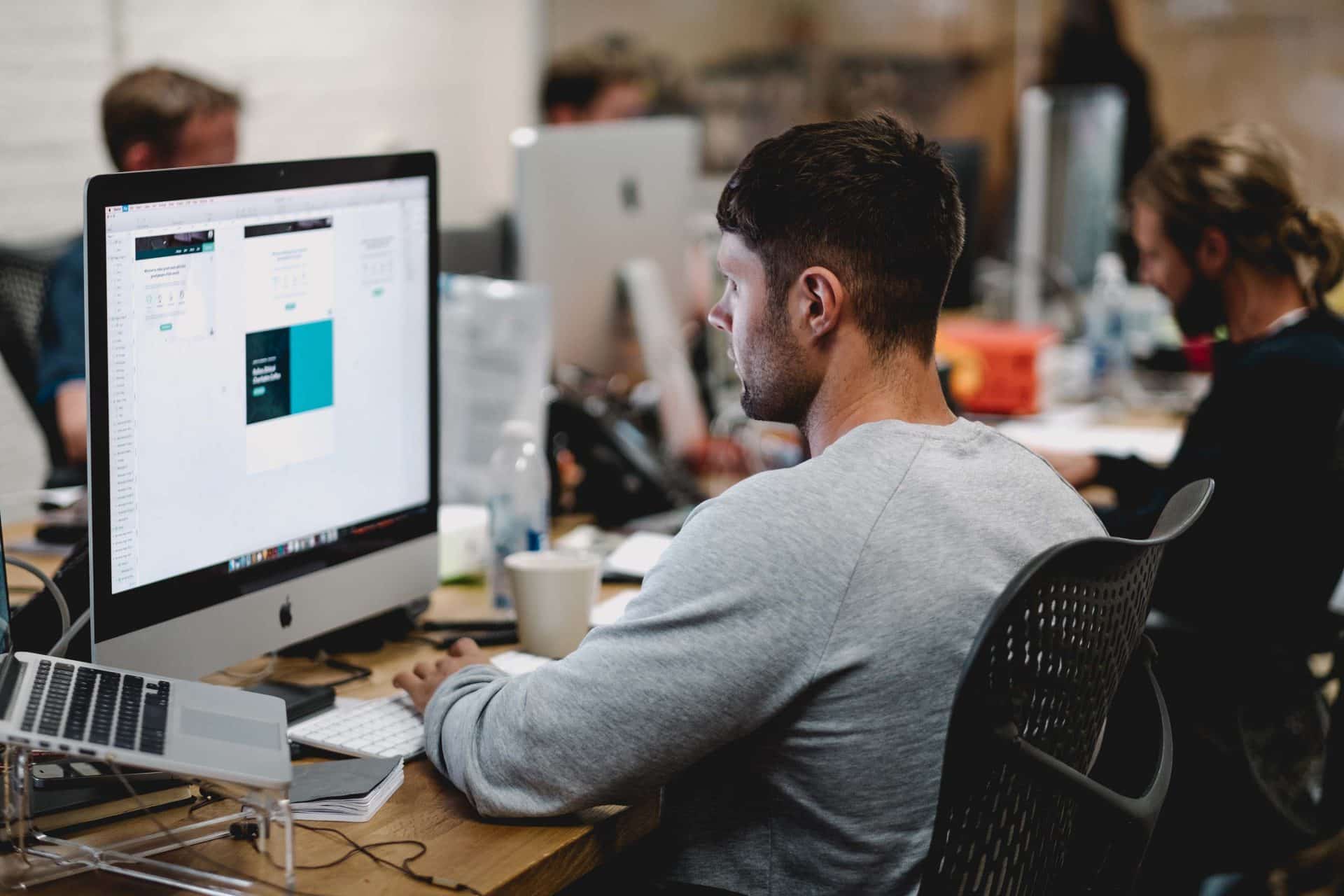 Homem digitando no teclado em frente a um computador