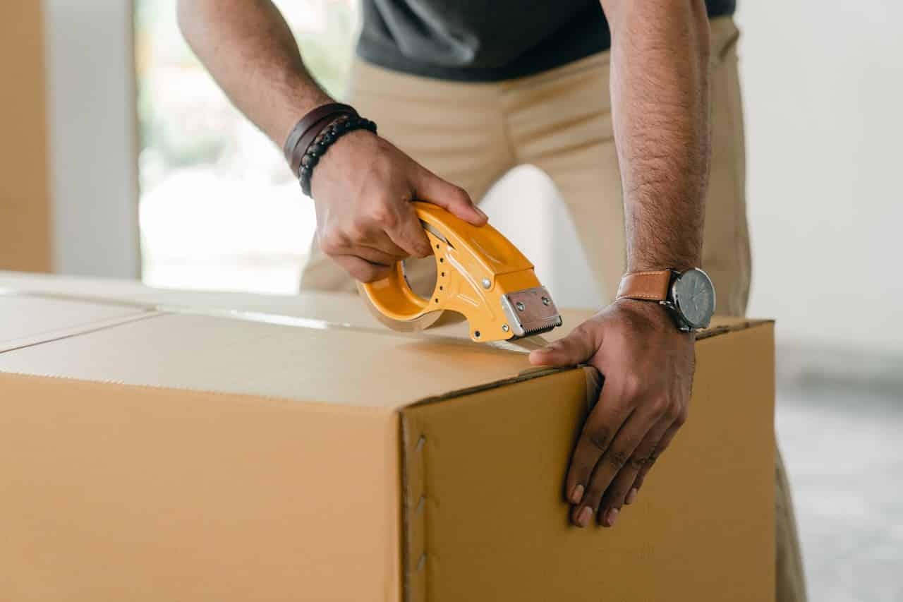 Homem fechando uma caixa de papelão