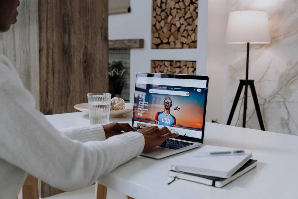 Mulher digitando em notebook com cadernos ao lado