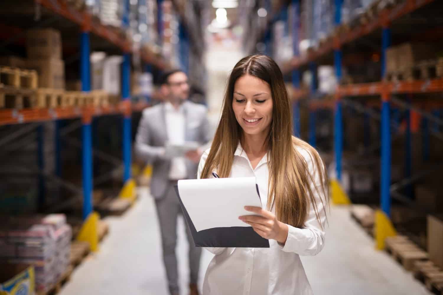 Uma mulher e um homem no centro logístico de uma empresa conferindo os produtos