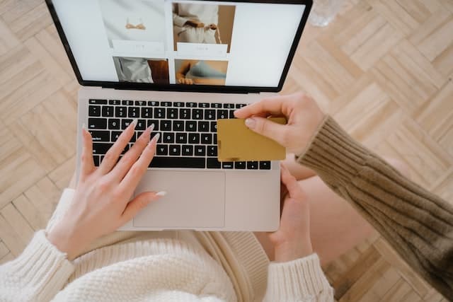 Mulher com cartão de crédito na mão fazendo compras online.